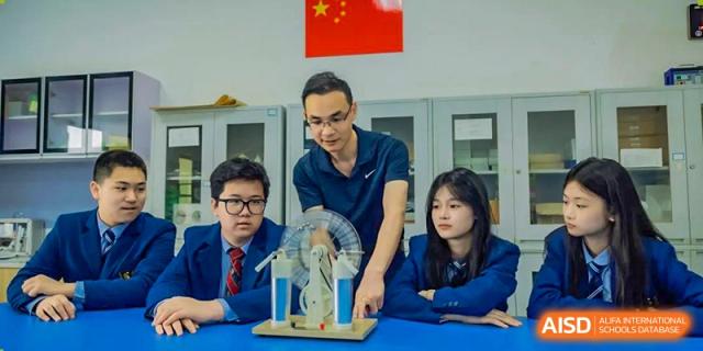 A teacher in a dark shirt demonstrates a science concept using a physics apparatus to a small group of attentive high school students at Changsha WES (Bilingual) Academy.