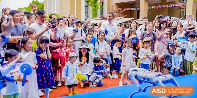 A large group of young children and a few adults gathered outdoors on a red carpet for a celebration or assembly at Changsha WES (Bilingual) Academy.