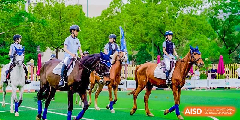 A student in a riding helmet on horseback participating in an equestrian activity or competition on a grassy field at Changsha WES (Bilingual) Academy.