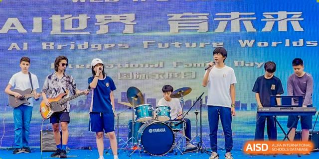 A student playing the drum set and other students performing on stage with a large "Futures" banner in the background at Changsha WES (Bilingual) Academy.