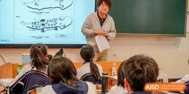 A male teacher giving a presentation or lesson to students in a classroom at Shenzhen Third Senior High School International Division A-Level Class.
