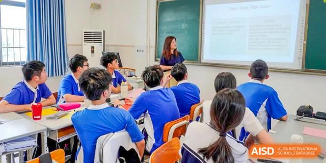 A teacher giving instructions to students seated in a brightly lit classroom at Shenzhen Third Senior High School International Division A-Level Class.