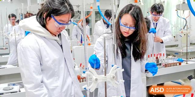Students working together on complex scientific equipment in the school chemistry lab at Shenzhen Third Senior High School International Division A-Level Class.