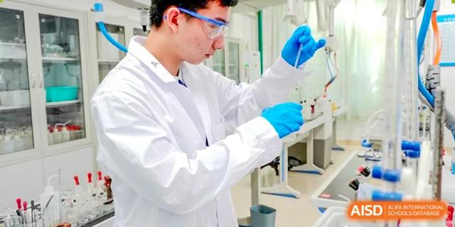Close-up of a student in a lab coat and blue gloves carefully conducting a chemical experiment at Shenzhen Third Senior High School International Division A-Level Class.