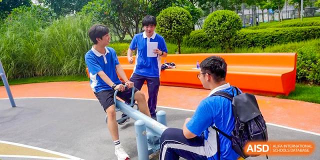 Students interacting outdoors, one holding a piece of paper, likely during a class activity or event at Shenzhen Third Senior High School International Division A-Level Class.