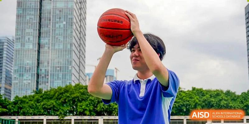 Close-up of a student in a blue shirt holding a basketball, preparing to shoot at Shenzhen Third Senior High School International Division A-Level Class.