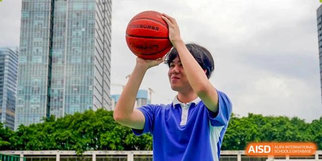 Close-up of a student in a blue shirt holding a basketball, preparing to shoot at Shenzhen Third Senior High School International Division A-Level Class.