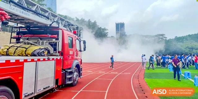 Fire truck spraying water near the running track during a fire safety drill or event at Shenzhen Third Senior High School International Division A-Level Class.