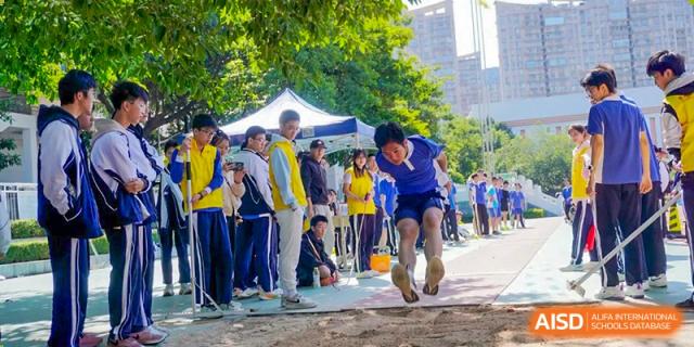 Student running and jumping into a sand pit during a long jump or triple jump event at Shenzhen Third Senior High School International Division A-Level Class.