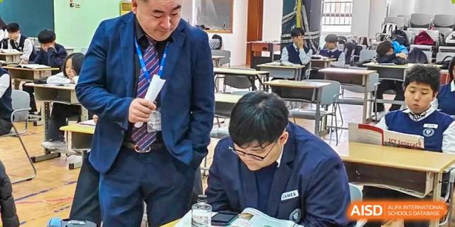A student in a school uniform studying or taking a test at a desk in a classroom at Weihai Zhongshi Foreign School (WZFS).