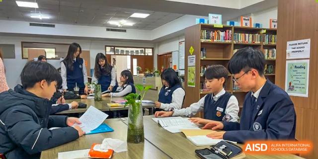 Students working on a project or studying together at a table in the school's library or common area at Weihai Zhongshi Foreign School (WZFS).