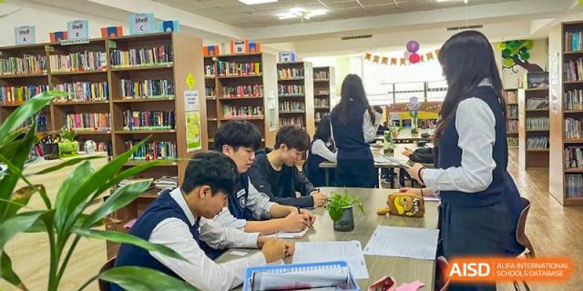 Students working together at a table in the school library or study area at Weihai Zhongshi Foreign School (WZFS).
