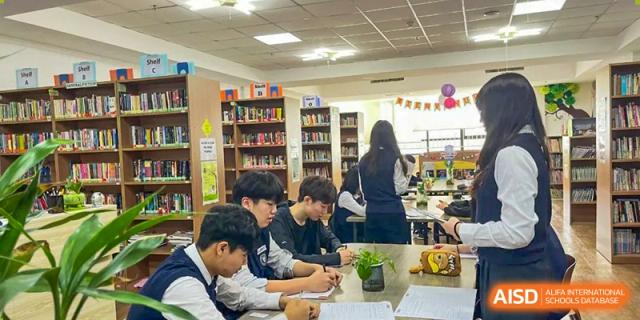 A close-up of students collaborating on a project or discussing work in the library at Weihai Zhongshi Foreign School (WZFS).