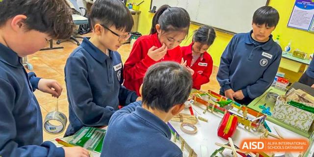 Students and adults seated at a table, engaging in a hands-on class or project at Weihai Zhongshi Foreign School (WZFS).