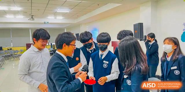 Students wearing school uniforms and face masks speaking with a teacher or administrator at Weihai Zhongshi Foreign School (WZFS).