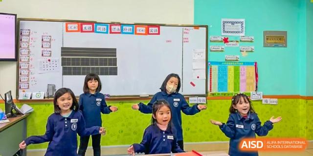 A young student smiling and interacting with a teacher in an elementary classroom at Weihai Zhongshi Foreign School (WZFS).