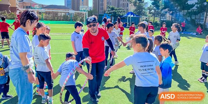 Students and a teacher playing a game on the grass field at Weihai Zhongshi Foreign School (WZFS).