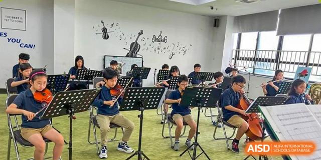 Students playing musical instruments like violins and cellos in an orchestra or ensemble rehearsal at Weihai Zhongshi Foreign School (WZFS).