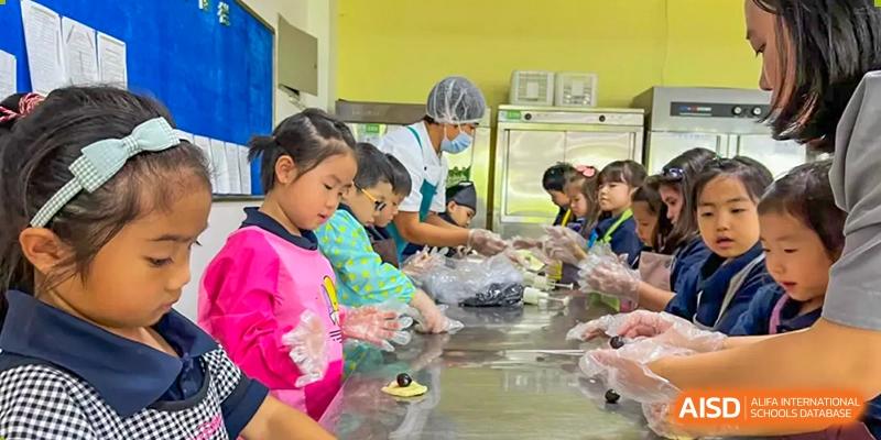 Young students participating in a cooking or food preparation activity with supervision at Weihai Zhongshi Foreign School (WZFS).