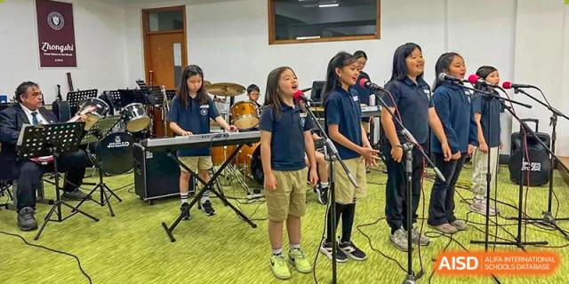 Students performing on stage in a band, with a student singing into a microphone at Weihai Zhongshi Foreign School (WZFS).