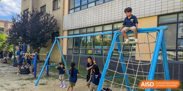 Students climbing and playing on outdoor jungle gym equipment at Weihai Zhongshi Foreign School (WZFS).