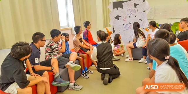Students sitting on the floor in a circle, engaged in a group activity at Alcanta International College.
