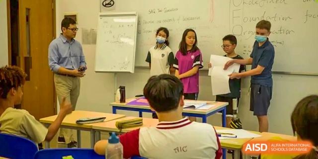 A student in a school uniform sitting at a desk and listening to the teacher at Alcanta International College.