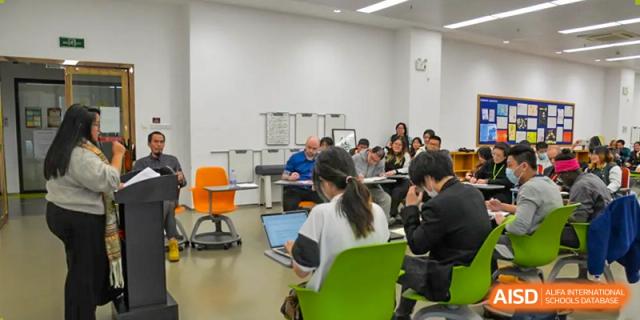 Students working with a teacher and using laptops during a classroom session at Alcanta International College.