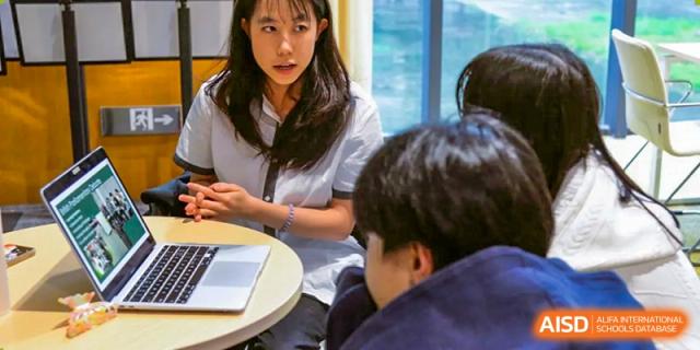 A close-up of three students looking at a tablet or laptop screen together and collaborating on a project at Alcanta International College.