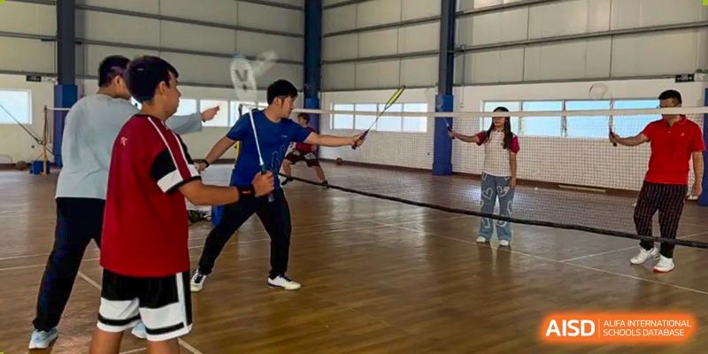 A student in fencing gear practicing with a foil in a gym at Alcanta International College.