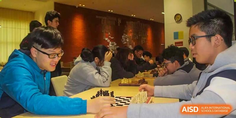 A group of students playing chess together in a quiet room at Alcanta International College.