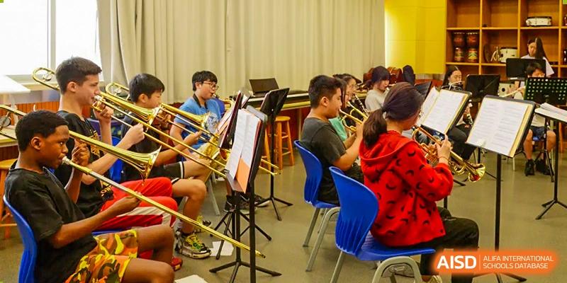 Students playing wind and brass instruments during a band rehearsal at Alcanta International College.