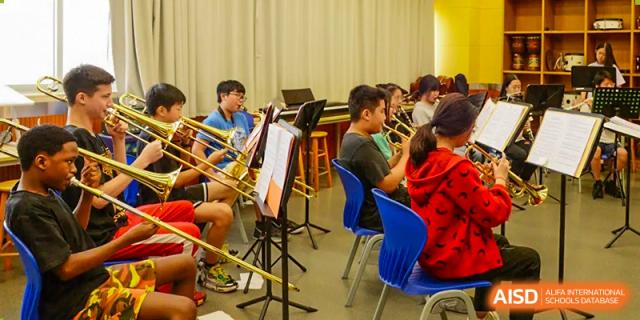 Students playing wind and brass instruments during a band rehearsal at Alcanta International College.