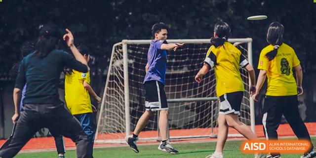 A male student running with a soccer ball on a field during a game at Alcanta International College.