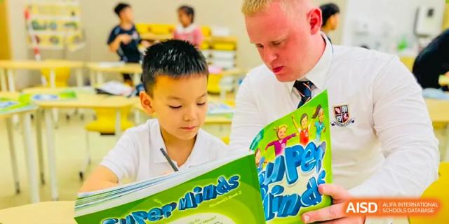 A foreign teacher at Changsha BeeMee Forest School (CBFS) reading a book with a young student in a classroom.