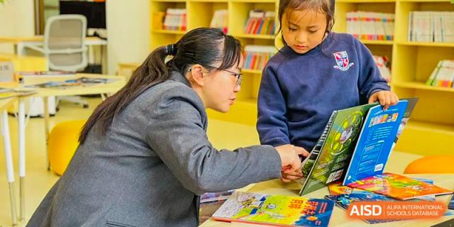 A teacher at Changsha BeeMee Forest School (CBFS) helping a student with a lesson on a laptop or tablet.