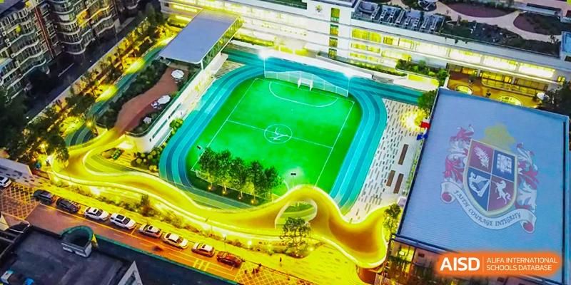 An aerial view of the modern sports complex and green football field at Changsha BeeMee Forest School (CBFS).