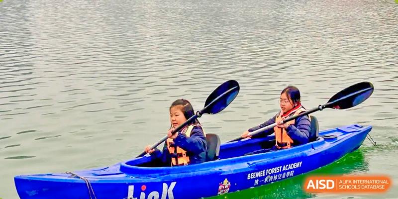 A young student from Changsha BeeMee Forest School (CBFS) paddling a kayak on a body of water while wearing a life vest.