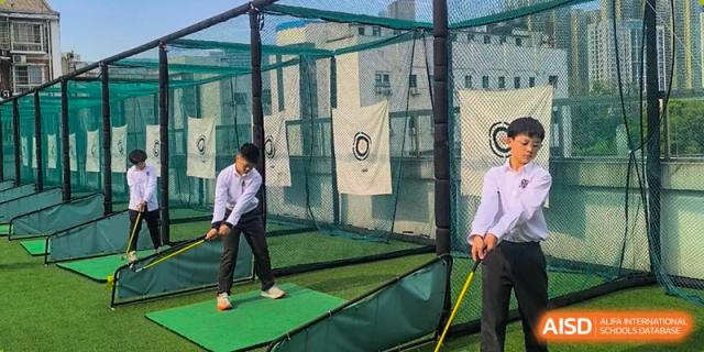 A student from Changsha BeeMee Forest School (CBFS) practicing a golf swing in an enclosed driving net outdoors.