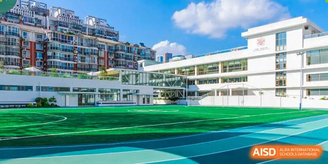 The green outdoor sports field and modern campus buildings of Changsha BeeMee Forest School (CBFS) on a sunny day.