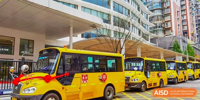 Yellow school buses parked outside the modern entrance of Changsha BeeMee Forest School (CBFS).
