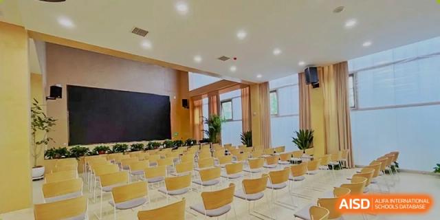 An interior view of a bright, modern classroom or lecture space at Changsha BeeMee Forest School (CBFS) with small wooden chairs.
