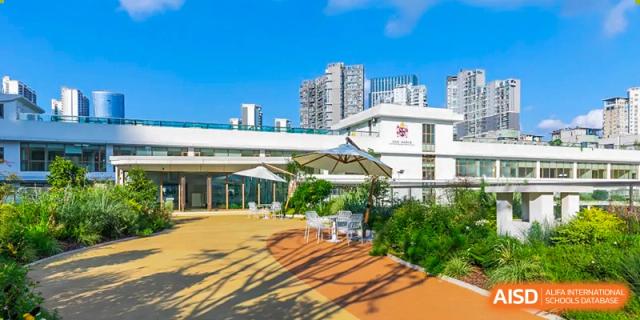 An outdoor patio area with white umbrellas and seating at Changsha BeeMee Forest School (CBFS), part of the main campus building.