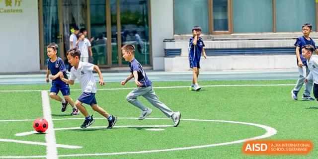 A student from Changsha BeeMee Forest School (CBFS) running on the green sports field during a physical education class or game.