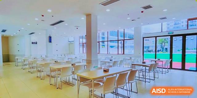 The bright, clean dining hall or cafeteria at Changsha BeeMee Forest School (CBFS) with tables and chairs.