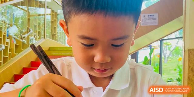 A close-up of a young male student from Changsha BeeMee Forest School (CBFS) looking down while eating his food.