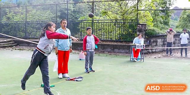 CHONGQING WEIMING SCHOOL student practicing basketball outdoors with an instructor on a green court.