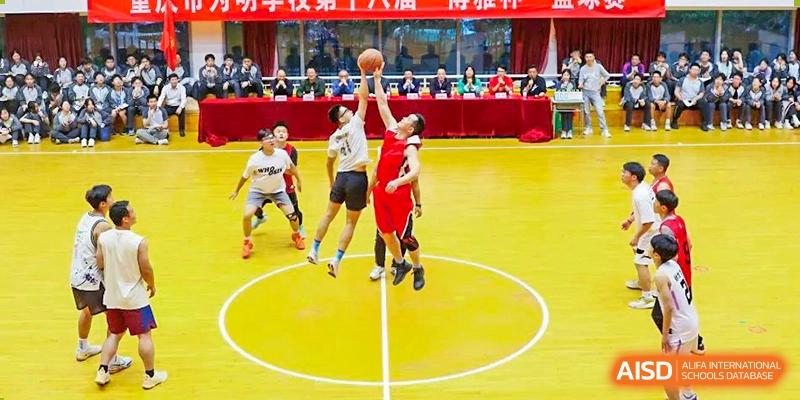 Intense basketball action with CHONGQING WEIMING SCHOOL students during a game, one student shooting a lay-up or jump shot on a bright yellow court.