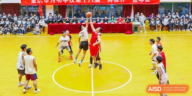 Intense basketball action with CHONGQING WEIMING SCHOOL students during a game, one student shooting a lay-up or jump shot on a bright yellow court.