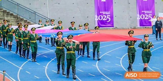 Military-style honor guards or a student marching team from CHONGQING WEIMING SCHOOL carrying a large banner or flag on a blue running track.